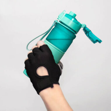 Female hand in a sports glove holds a sports water bottle