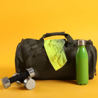 Sports bag and gym equipment on yellow background