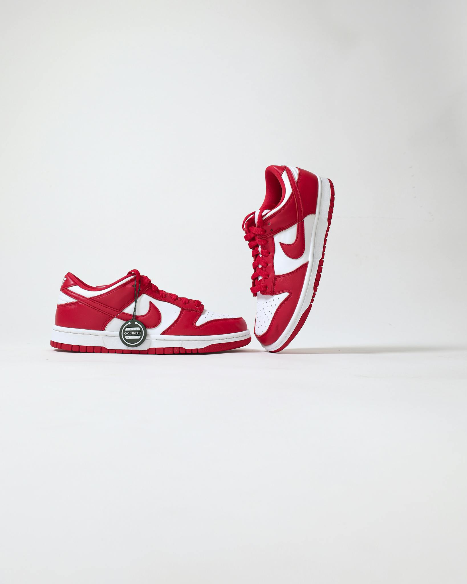 Red and white sneakers displayed creatively against a white backdrop, highlighting their sporty design.